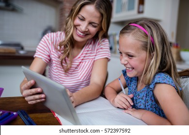 Mother using a digital tablet while helping daughter with her homework at home, Social distancing and self isolation in quarantine lockdown