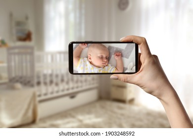 Mother Using Modern Mobile Phone As Baby Monitor At Home