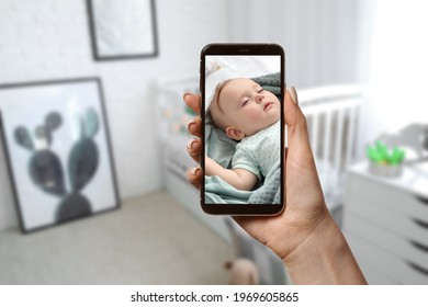 Mother Using Modern Mobile Phone As Baby Monitor At Home