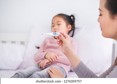 Mother Using Thermometer With Her Girl Kid Daughter For Sickness And Fever