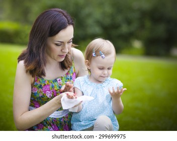 Mother Using Wet Wipes For Her Daughter On White Park Background