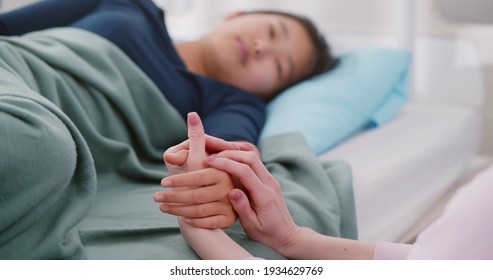 Mother Visiting Sick Asian Daughter In Hospital And Holding Hands. Teen Korean Child Patient Lying In Bed Talking And Holding Hands With Mom Visiting In Hospital Ward