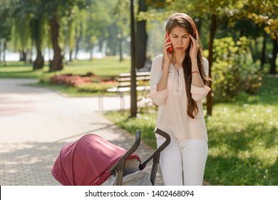 Mother, Walking With Baby, Talking On The Phone And Can't Hear Anything. Woman Annoyed By Poor Signal.