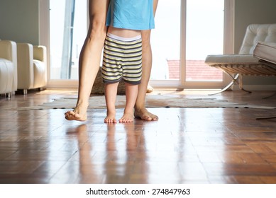 Mother Walking With Little Boy At Home On Wood Floor