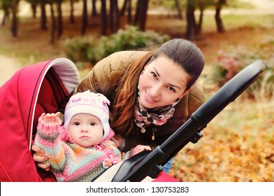 Mother Walking In The Park With Her Baby In Stroller