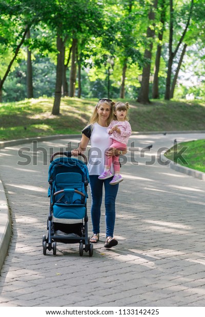 Mother\
walking while pushing a stroller in the\
park