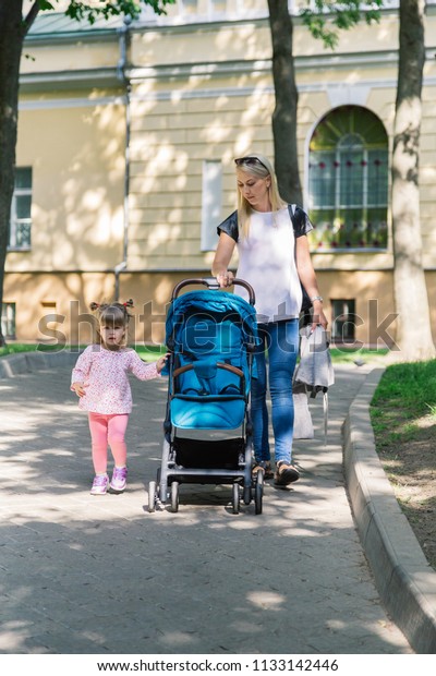 Mother\
walking while pushing a stroller in the\
park