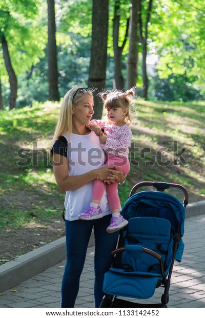 Mother
walking while pushing a stroller in the
park