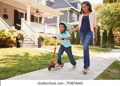 Mother Walks With Son As He Rides Scooter Along Sidewalk - Shutterstock ID 793876465