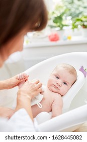 Mother Washes Baby Caring With A Washcloth In Baby Bath