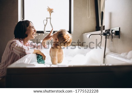 Mother washing little son in bathroom