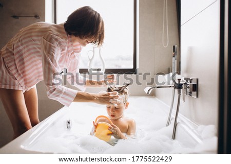 Mother washing little son in bathroom