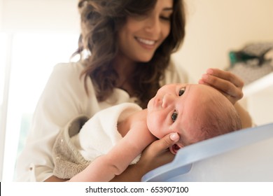 Mother Washing A Newborn Baby In A Bath Tub