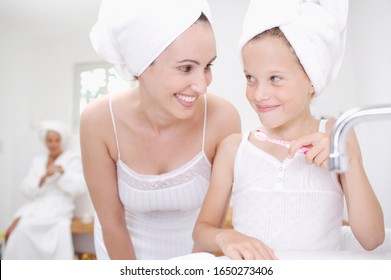 Mother watching daughter brush teeth