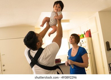 Mother Watching Father Lifting Baby In Mid-air