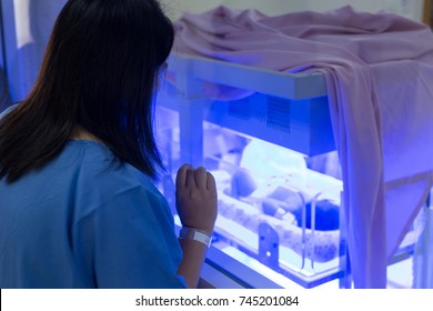 Mother Watching At The Newborn Baby With Hyperbilirubinemia / Neonatal Jaundice Under Blue UV Light For Phototheraphy On Infant Warmer In Neonatal Intensive Care Unit