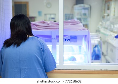 Mother Watching At The Newborn Baby With Hyperbilirubinemia / Neonatal Jaundice Under Blue UV Light For Phototheraphy On Infant Warmer In Neonatal Intensive Care Unit