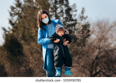 Mother Wearing Medical Mask Supervising Child Playing Outdoors. Overprotective Mom Watching Over Child Playing Outdoors
