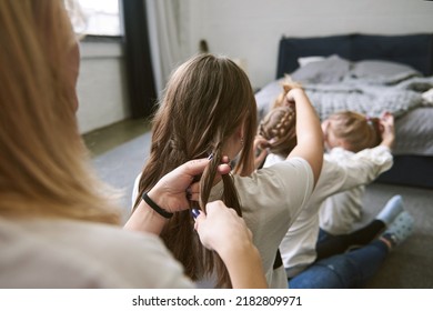 Mother Weaving Braids With Her Toddler Daughters At Home. Big Family Concept.  Spending Time Together. Daughter Mother Vibes