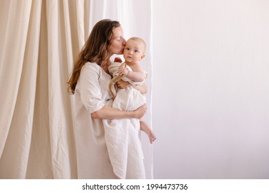 mother in white clothes kiss a baby. Purity innocence sanctity of motherhood. Mom and child. happiness of motherhood. Eco parenting vegan. Closeness to nature. Happy childhood care. Natural fabric - Shutterstock ID 1994473736