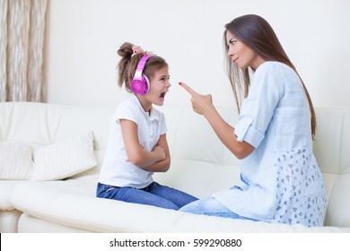 Mother Will Raise A Daughter Of A Teenage Girl, Girl Screams In Response To Listening To Headphones. Mom Threatens A Finger. Aggressive Teenager. Caucasian Woman And Girl Teen Screaming, Yelling   