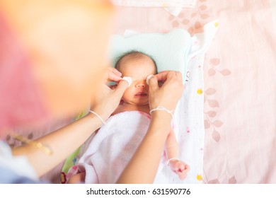 Mother Is Wiping The Baby Eyes With Normal Saline Solution.