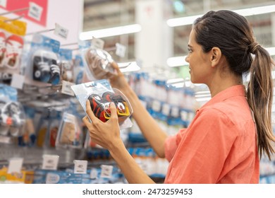 Mother woman carefully examines a modern, decision making baby shoe in baby store, mindful parent, seeking quality and safety in children products family planning, baby care products, shopping - Powered by Shutterstock