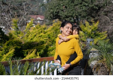 A mother, woman, female, girl playing, cuddling, smiling, hugging, holding  cute beautiful lovely girl, child, kid, daughter in a garden, vacation, place, hotel, hill station, picnic. Single mother. - Shutterstock ID 2144435791