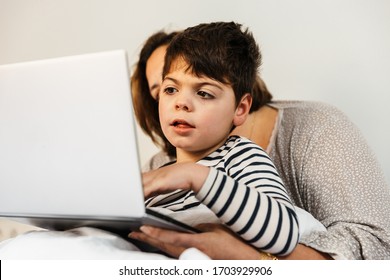 A Mother Woman And Her Child With Multiple Disabilities (handicap, Disability) Play With The Laptop In Bed. They Are In Pajamas, And They Are Happy And Smiling.