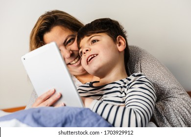 A Mother Woman And Her Child With Multiple Disabilities (handicap, Disability) Play With The Laptop In Bed. They Are In Pajamas, And They Are Happy And Smiling.