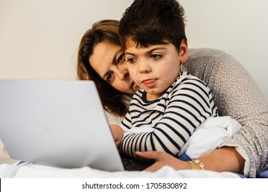 A Mother Woman And Her Child With Multiple Disabilities (handicap, Disability) Play With The Laptop In Bed. They Are In Pajamas, And They Are Happy And Smiling.