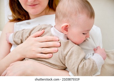 A mother woman holds an infant baby to regurgitate excess air after breastfeeding. Mom with a child boy holds vertically after feeding