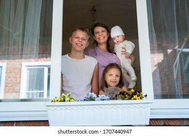 Mother woman with a newborn baby and girl child preschooler and son teenager boy looking out the window during isolation from the coronavirus pandemic - Shutterstock ID 1707440947