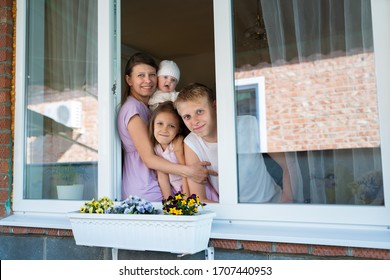 Mother woman with a newborn baby and girl child preschooler and son teenager boy looking out the window during isolation from the coronavirus pandemic - Shutterstock ID 1707440953