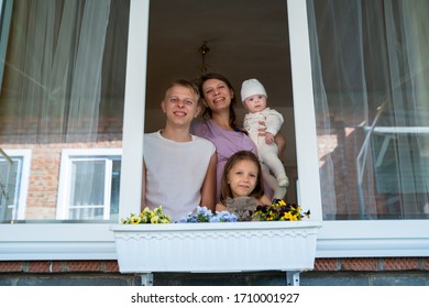 Mother woman with a newborn baby and girl child preschooler and son teenager boy looking out the window during isolation from the coronavirus pandemic - Shutterstock ID 1710001927