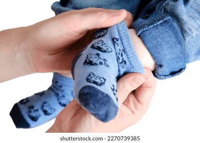A mother woman wears blue socks to a foot baby boy, isolated on a white background. Mom dresses a leg child in clothes. Kid nine months old