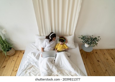 Mother Work From Home Remotely While Being On Coronavirus Sick Leave Lying In Bed With Cute Preschool Child Boy On Quarantine. Young Single Mom Caring For Little Son Spend Work Day With Kid In Bedroom