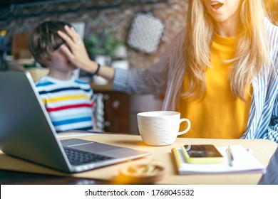 Mother Working From Home And Online Education With Kid. Stressed With Computer And Phone. Child Make Noise And Disturb Woman At Work. Homeschooling And Freelance Job. Smiling Boy Playing At Kitchen