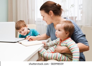 A mother working at home and parenting her two children.
