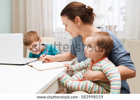 A mother working at home and parenting her two children.
