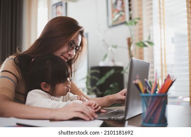 Mother working at home-office with daughter on her lap