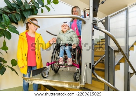 Mother with a young child living with cerebral palsy using electric wheelchair lift to access public building. Special lifting platform for wheelchair users. Disability stairs lift facility. Photo stock © 