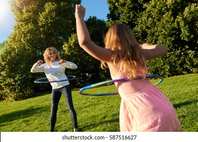 Mother and young daughter playing with hula hoops outside - Powered by Shutterstock