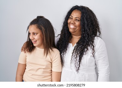 Mother And Young Daughter Standing Over White Background Looking Away To Side With Smile On Face, Natural Expression. Laughing Confident. 