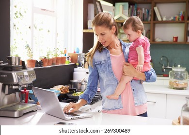 Mother With Young Daughter Using Laptop In Kitchen - Powered by Shutterstock