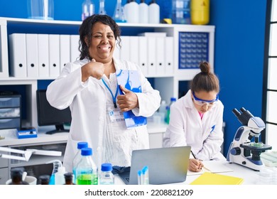 Mother And Young Daughter Working At Scientist Laboratory Pointing Finger To One Self Smiling Happy And Proud 