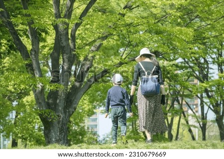 a mother and young son walking in the park
