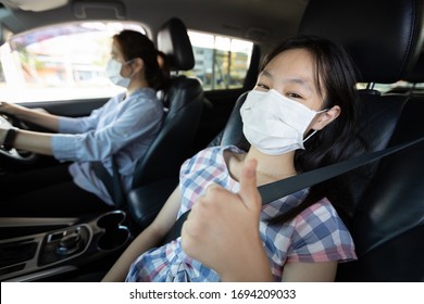 Mother,daughter Fastening Seat Belt In Car,woman Driving Safety On The Road,child Girl Thumbs Up Wearing A Protective Mask Before Leaving The House During The Coronavirus Pandemic,spread Of Covid-19