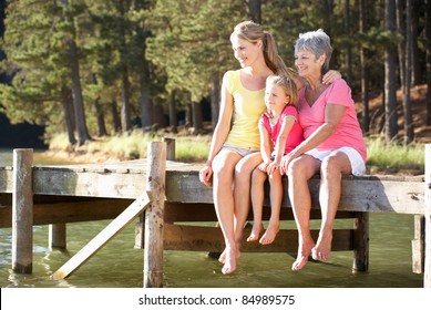 Mother,daughter and grandmother sitting by lake