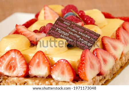 Motherday fruit tart closeup, yellow cream with passion fruit flavor and red berries coulis and strawberries on caramel crust